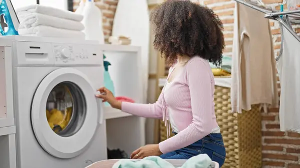 African american woman washing clothes at laundry room