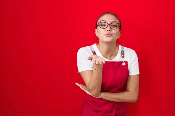 Młoda Latynoska Kobieta Ubrana Fartuch Kelnerki Czerwonym Tle Patrząca Kamerę — Zdjęcie stockowe