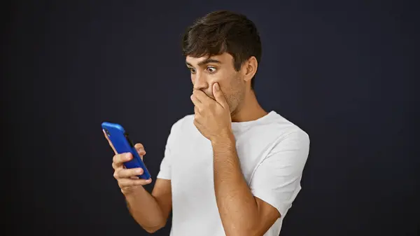 Jonge Spaanse Man Zoek Naar Smartphone Met Verrassende Expressie Geïsoleerde — Stockfoto