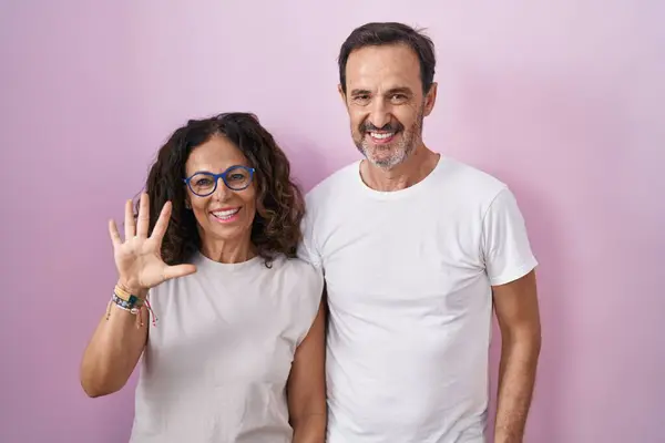Para Hiszpanów Średnim Wieku Różowym Tle Pokazująca Wskazująca Palcami Numer — Zdjęcie stockowe
