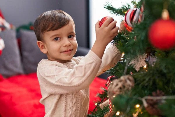 自宅でクリスマスツリーを飾る自信を持って微笑む愛らしいヒスパニックの少年 — ストック写真