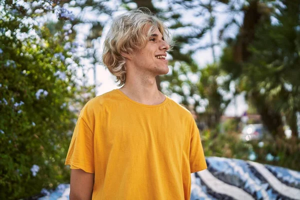 Young blond man smiling confident looking to the side at park