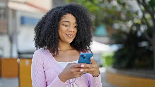 在公园用智能手机微笑的非裔美国女人 — 图库照片