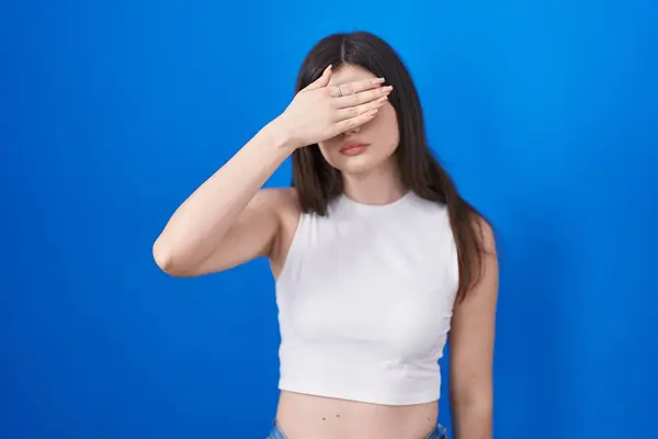 Young Caucasian Woman Standing Blue Background Covering Eyes Hand Looking — Stock Photo, Image