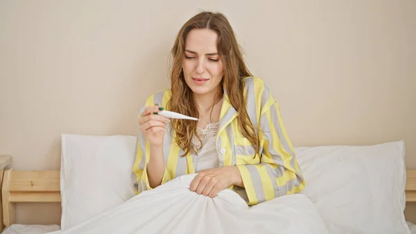 Mujer Rubia Joven Sentada Cama Estando Enferma Midiendo Temperatura Dormitorio —  Fotos de Stock