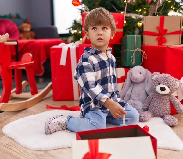 可爱的他的惊慌失措的孩子在家里的圣诞树旁玩着圈圈玩具 — 图库照片