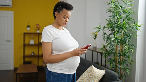 Νεαρή Έγκυος Γυναίκα Που Χρησιμοποιεί Smartphone Στέκεται Στο Σπίτι — Φωτογραφία Αρχείου