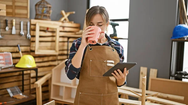 Attractive Young Blonde Carpenter Woman Coffee Hand Navigating Touchpad Amidst — Stock Photo, Image