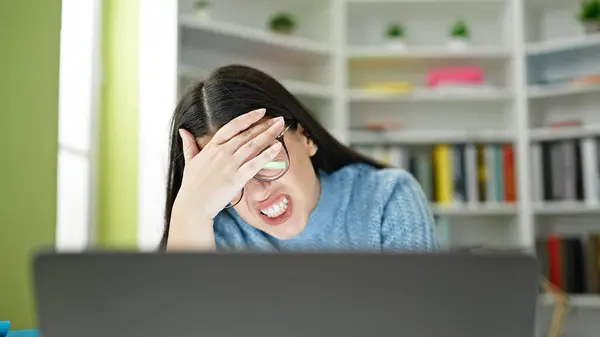 Young hispanic woman student upset using laptop at library university