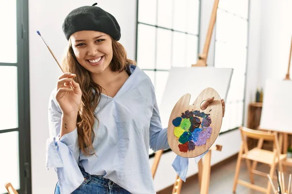 Joven Hermosa Artista Hispana Sonriendo Confiada Sosteniendo Pincel Paleta Estudio — Foto de Stock