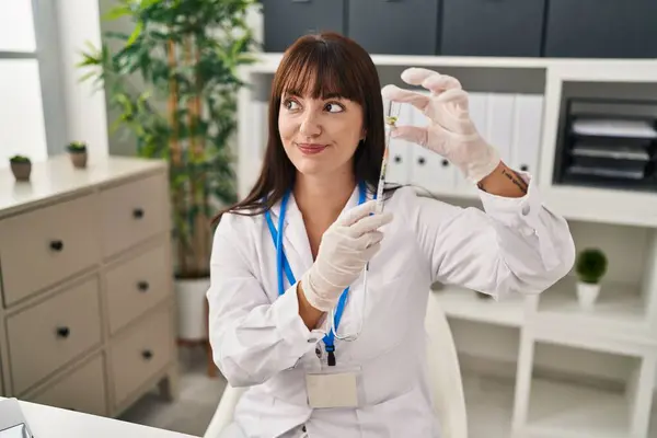 若いブルネット医師の女性は 注射器とワクチンを持って横を見つめ 考えを遠ざける — ストック写真