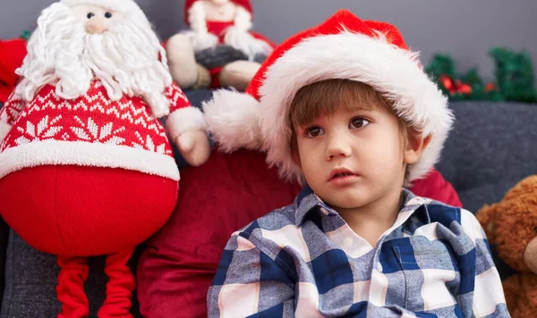 可爱的他惊慌失措的儿子坐在沙发上 坐在家里的圣诞装饰品旁 — 图库照片