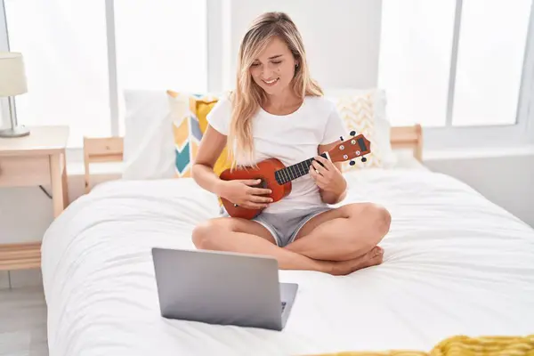 Young Blonde Woman Having Online Ukulele Lesson Sitting Bed Bedroom — Stock Photo, Image