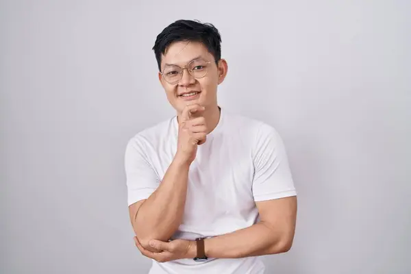 Beyaz Arka Planda Duran Asyalı Genç Adam Elleri Çenesinde Soru — Stok fotoğraf