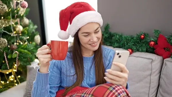 Молодая Белая Женщина Празднует Рождество Используя Смартфон Пьющий Кофе Дома — стоковое фото