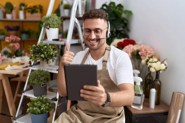 Hispanic man with beard working at florist shop doing video call smiling happy and positive, thumb up doing excellent and approval sign