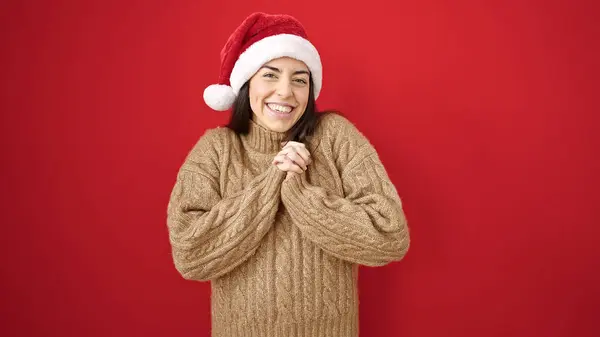 年轻美丽的惊慌失措的女人带着自信的笑容 戴着圣诞礼帽 披着孤零零的红色背景 — 图库照片