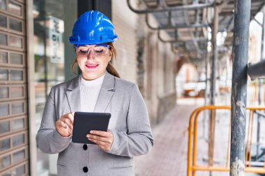 Genç, güzel İspanyol bir mimar sokakta dokunmatik ped kullanarak gülümsüyor.