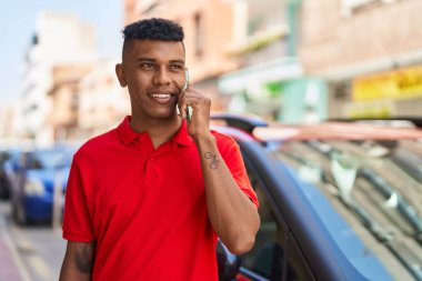 Genç Latin adam gülümsüyor. Kendine güveniyor. Akıllı telefondan konuşuyor.