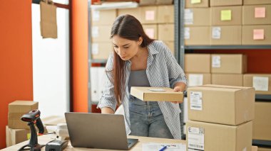 Genç, güzel İspanyol kadın, iş kadını. Ofiste dizüstü bilgisayar paketi kullanıyor.