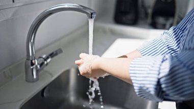 Genç ve güzel İspanyol kadın mutfakta ellerini yıkıyor.