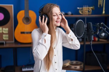 Genç beyaz kadın sanatçı müzik stüdyosunda şarkı söylüyor.