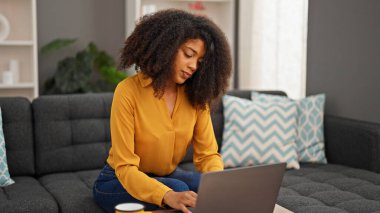 African american woman using laptop sitting on sofa at home
