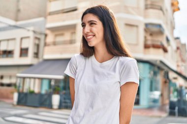 Young beautiful hispanic woman smiling confident looking to the side at street