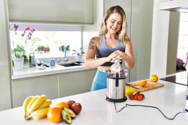 Young woman smiling confident using blender at kitchen