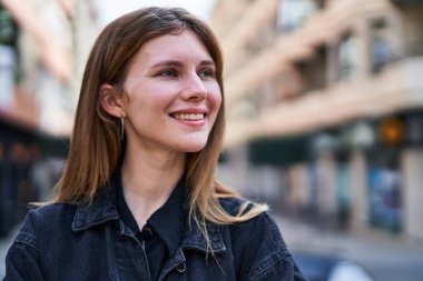 Young blonde woman smiling confident looking to the side at street