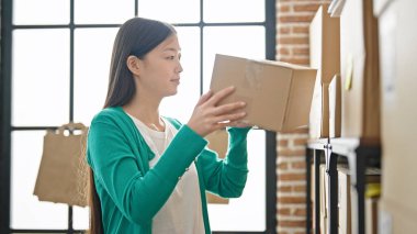 Genç Çinli kadın ecommerce işçisi ofiste raflara paket koyuyor.