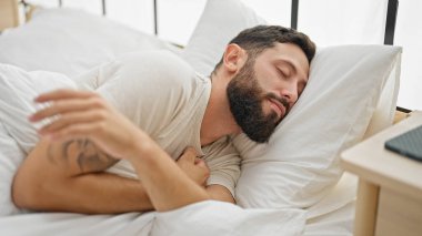 Genç İspanyol adam yatakta uzanıp yatak odasında uyuyor.