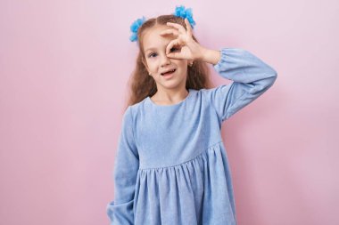 Pembe arka planda duran küçük kız gülümsüyor. Mutluluktan gülümsüyor. 