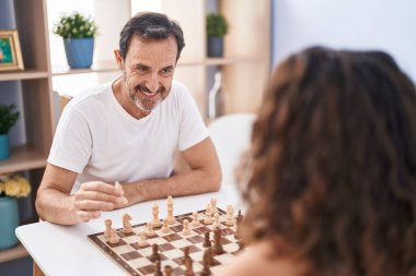 Man and woman smiling confident playing chess game at home