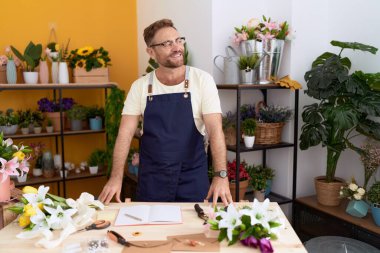 Çiçekçide kendine güvenen orta yaşlı bir çiçekçi.