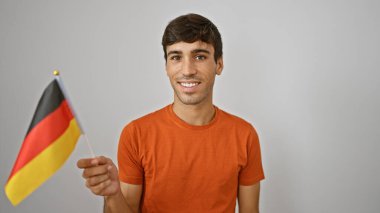 Neşeden patlayan, kendine güvenen İspanyol genç adam gelişigüzel ayakta, gülümseyen, elinde Alman bayrağı tutan, beyaz arka planda izole edilmiş, vatansever bir ifade sergiliyor.