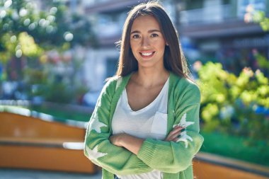 Parkta kollarını kavuşturmuş genç, güzel İspanyol bir kadın.