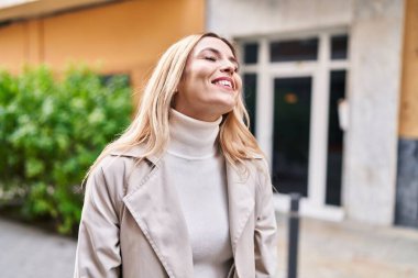 Young blonde woman smiling confident looking to the side at street