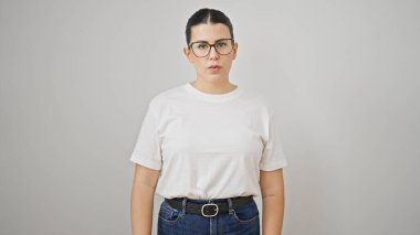 Soyutlanmış beyaz arka planda ciddi bir ifadeyle duran genç, güzel İspanyol kadın.