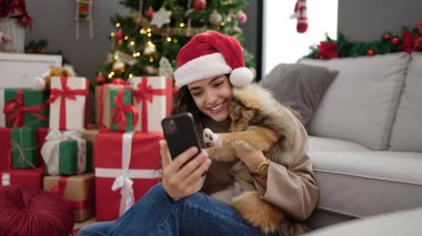 Köpekli genç İspanyol kadın, akıllı telefonla Noel 'i evde kutlayarak selfie çekiyor.