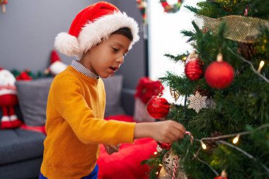 Evde Noel ağacı süsleyen sevimli İspanyol çocuk.