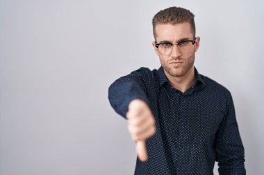 İzole edilmiş arka planda duran genç beyaz adam mutsuz ve kızgın görünüyor. Reddedilmiş ve olumsuz bir hareket sergiliyor. kötü ifade. 