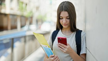 Genç ve güzel bir kız öğrenci okulda ciddi yüzlü akıllı telefon kullanıyor.