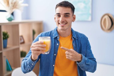 Yakışıklı İspanyol adam, bir bardak portakal suyu içip gülümsüyor. 