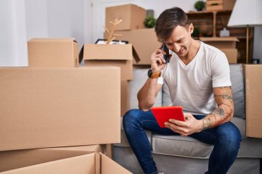 Genç adam yeni evinde kredi kartıyla akıllı telefondan konuşuyor.