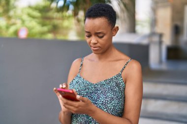 Sokakta akıllı telefon kullanan Afro-Amerikalı kadın.