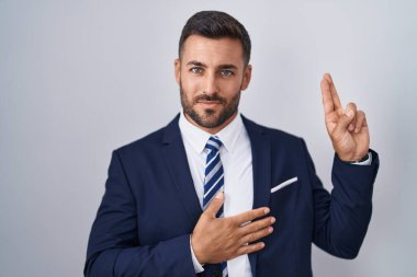 Yakışıklı, takım elbiseli ve kravatlı, gülümseyen, elleri göğsünde ve parmakları havada küfür eden, sadakat yemini eden bir İspanyol. 