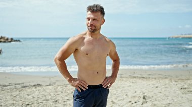 Plajda rahat bir ifadeyle duran genç bir turist.