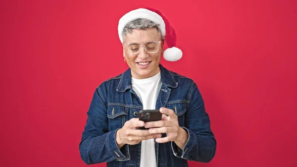 Junger Kaukasischer Mann Mit Weihnachtsmütze Und Smartphone Lächelt Über Isolierten — Stockfoto