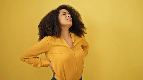 stock image African american woman suffering for backache over isolated yellow background